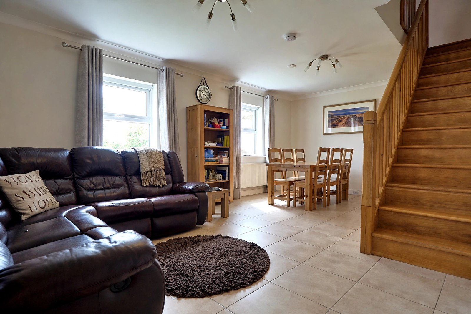 Living room with dark leather sofas, dining table and wooden staircase — enhanced sample photo