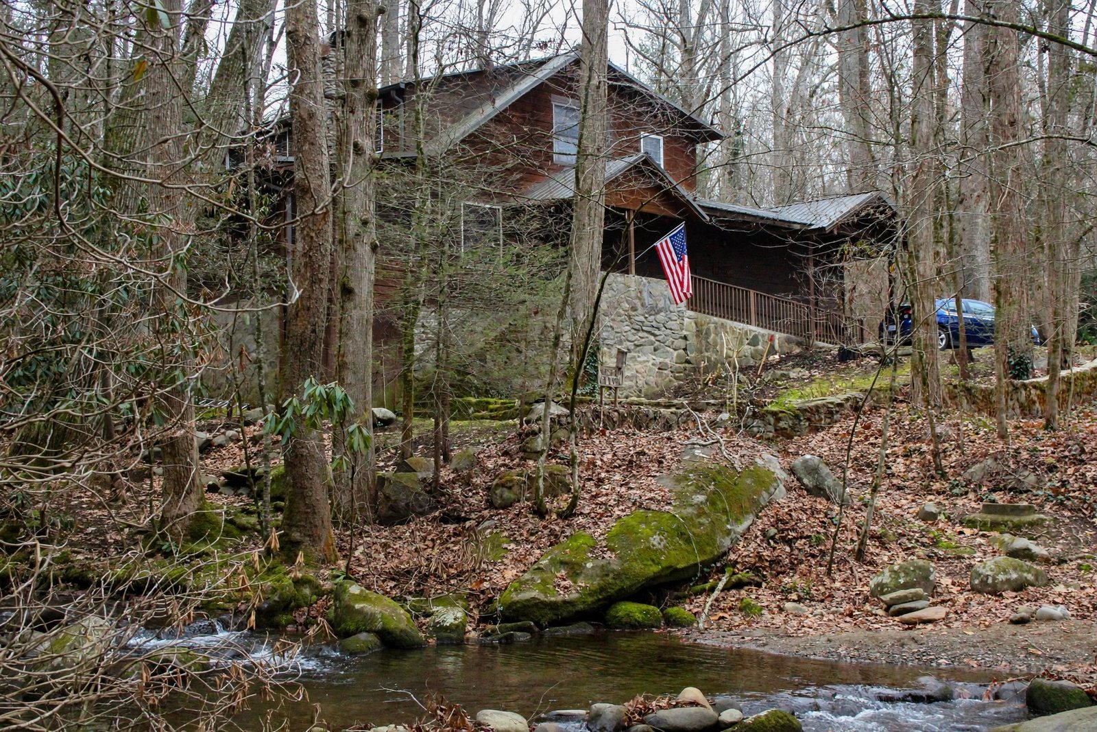 Cabin seen through bare trees above a small stream — enhanced sample photo