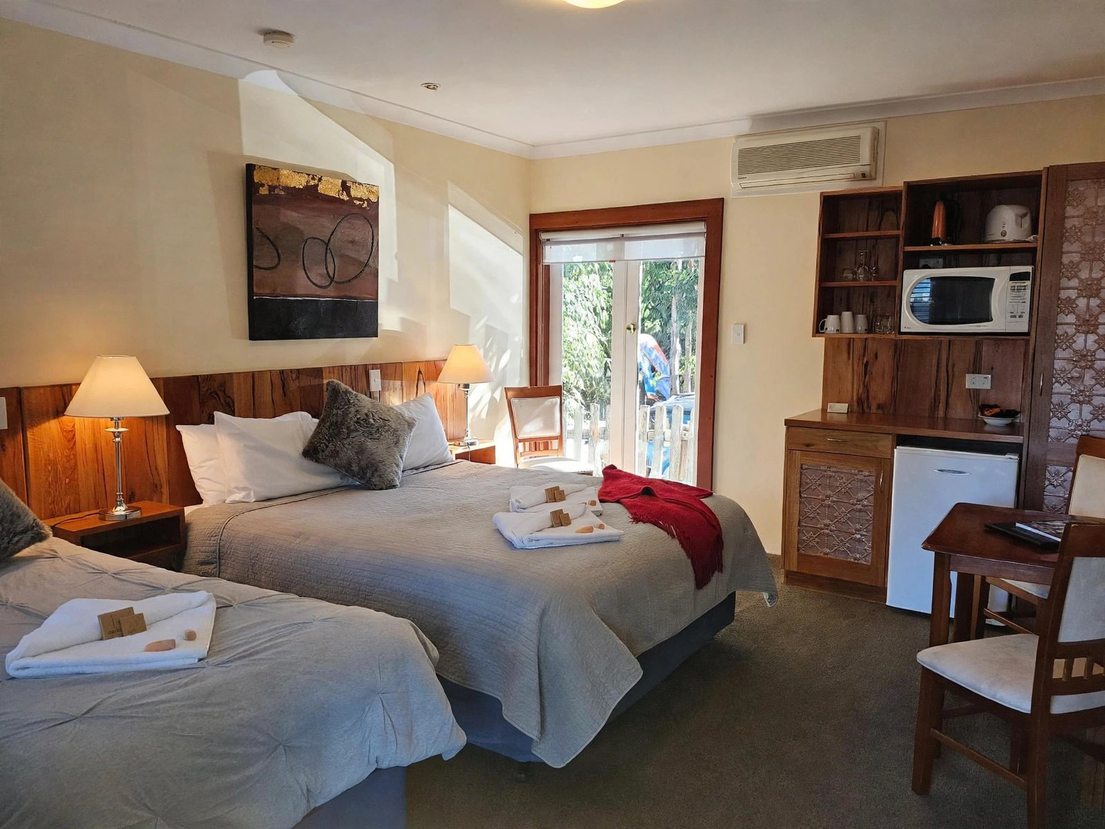 Triple room with three beds, kitchenette and doors to a deck — enhanced sample photo