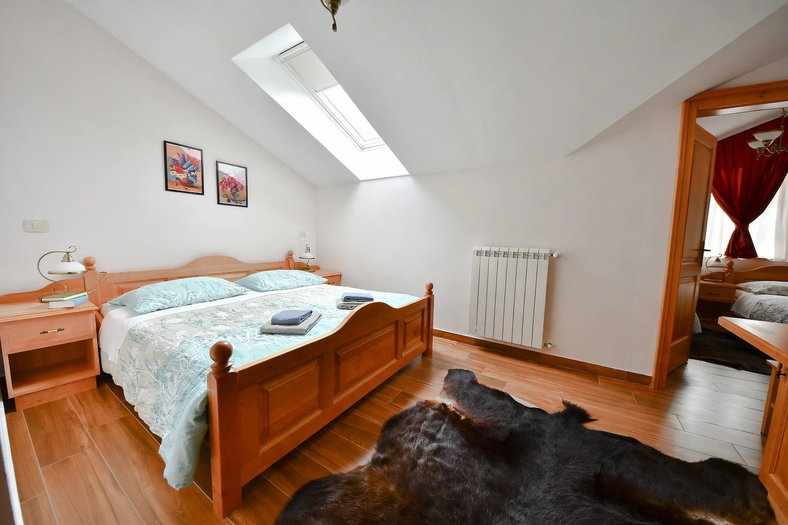 Attic bedroom with a wooden bed under a skylight and a cowhide rug — enhanced sample photo