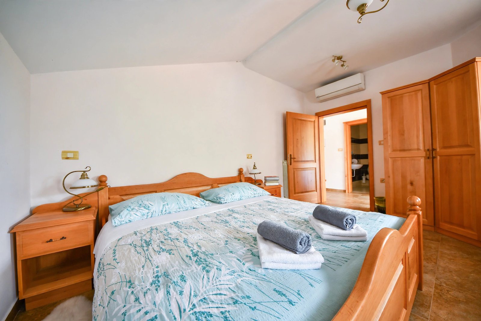 Double room with a wooden bed, floral bedding and a wardrobe — enhanced sample photo